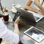 reunión optimum ventas dos personas tomando un café con ordenador, móvil y tablet